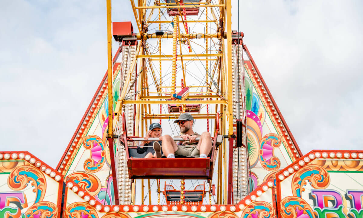 Child and parent on ferris wheel in the main arena of We Out Here Festival.